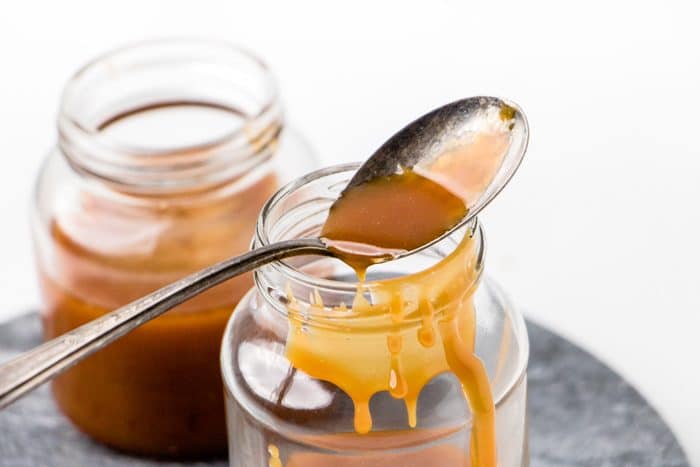 a spoon with dripping caramel sauce which will be used in making vegan coffee creamer