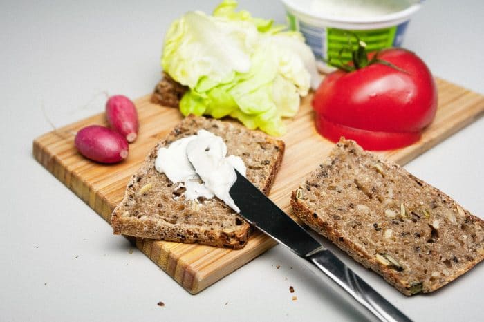 butter spread into a slice of bread plus other fresh vegetables used for making sandwich
